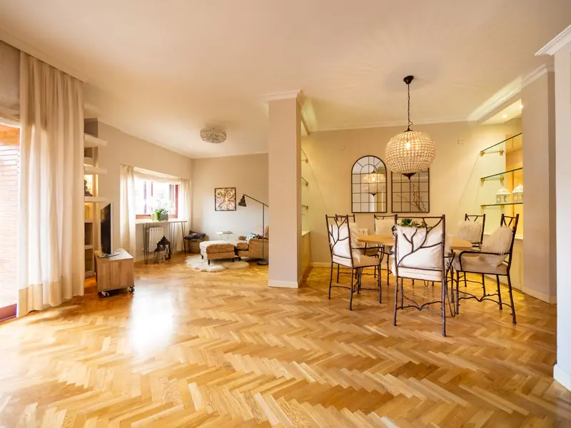 Living and dining room with an oak herringbone floor, a rattan pendant and a dining table